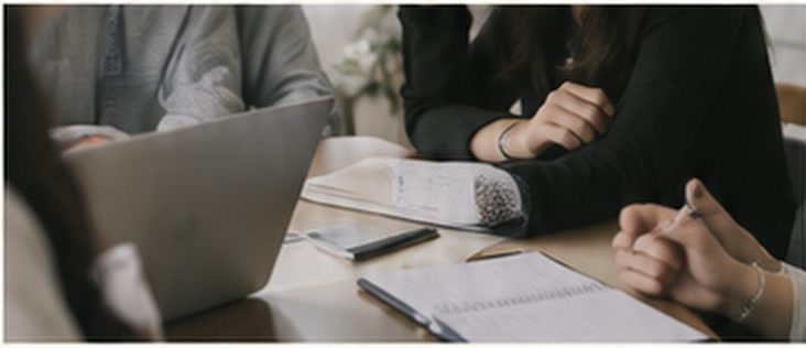 Two people reviewing notes and a laptop across a table during an interview.